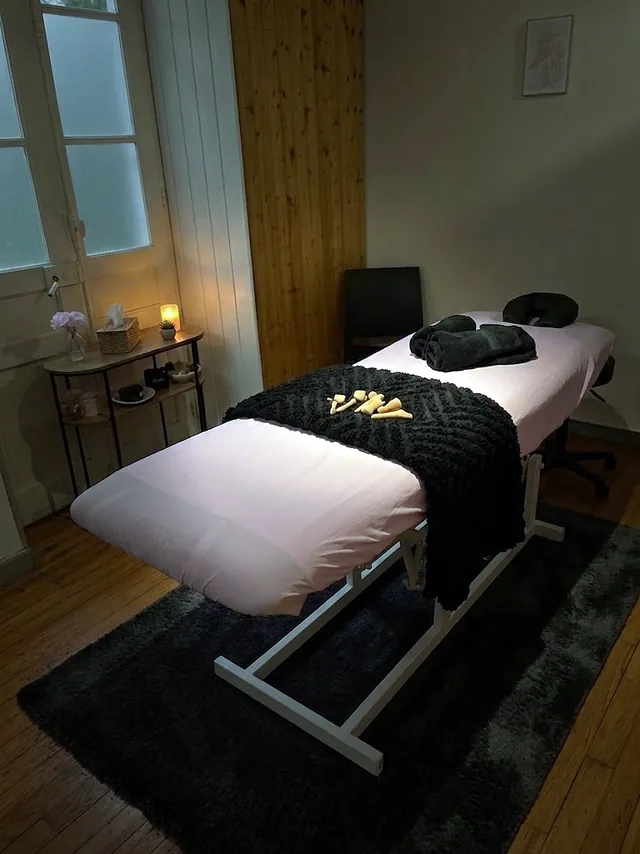 Le cabinet d’Olivia à Pau : une table de massage dressée de rose et de noir, ses outils de madérothérapie en bois, à la lumière d’une bougie